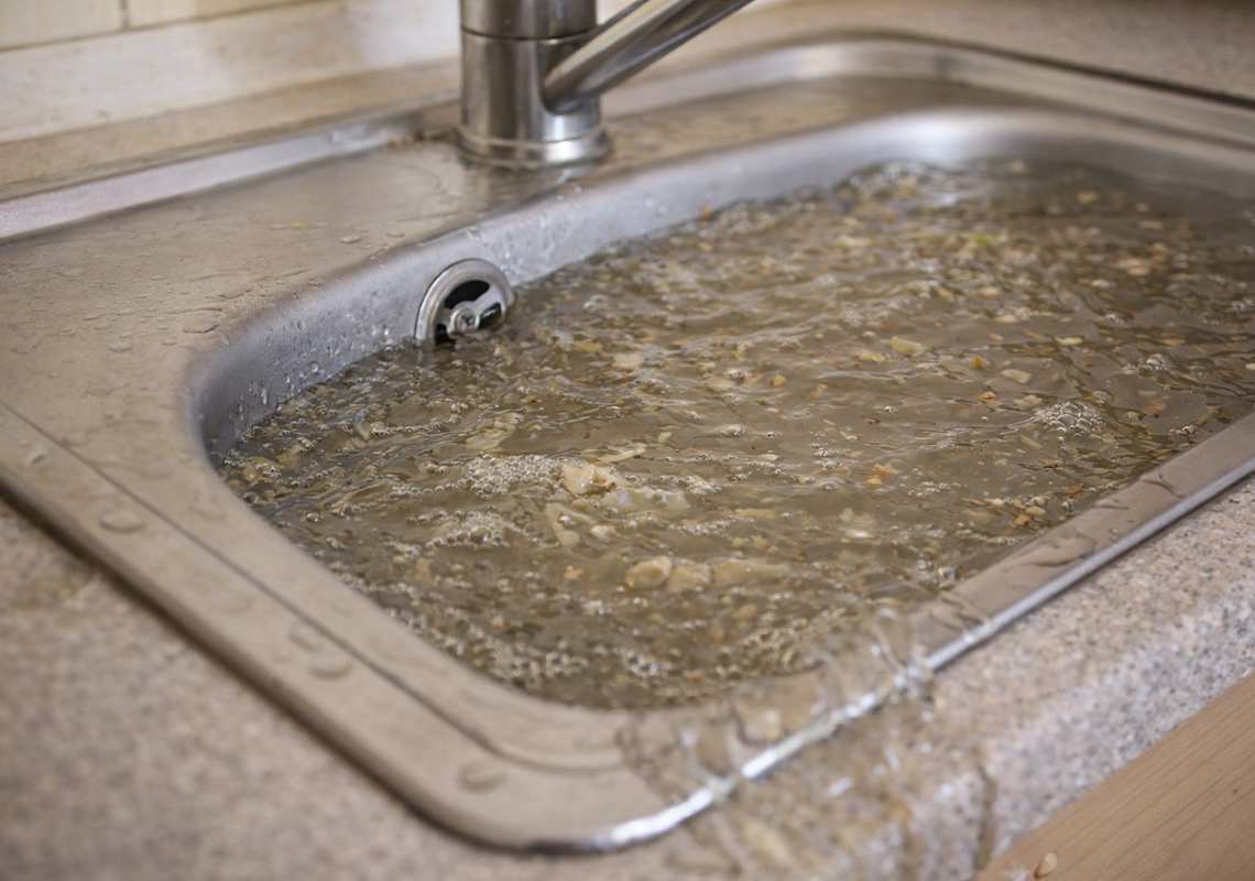 Clogged kitchen sink filled with standing water